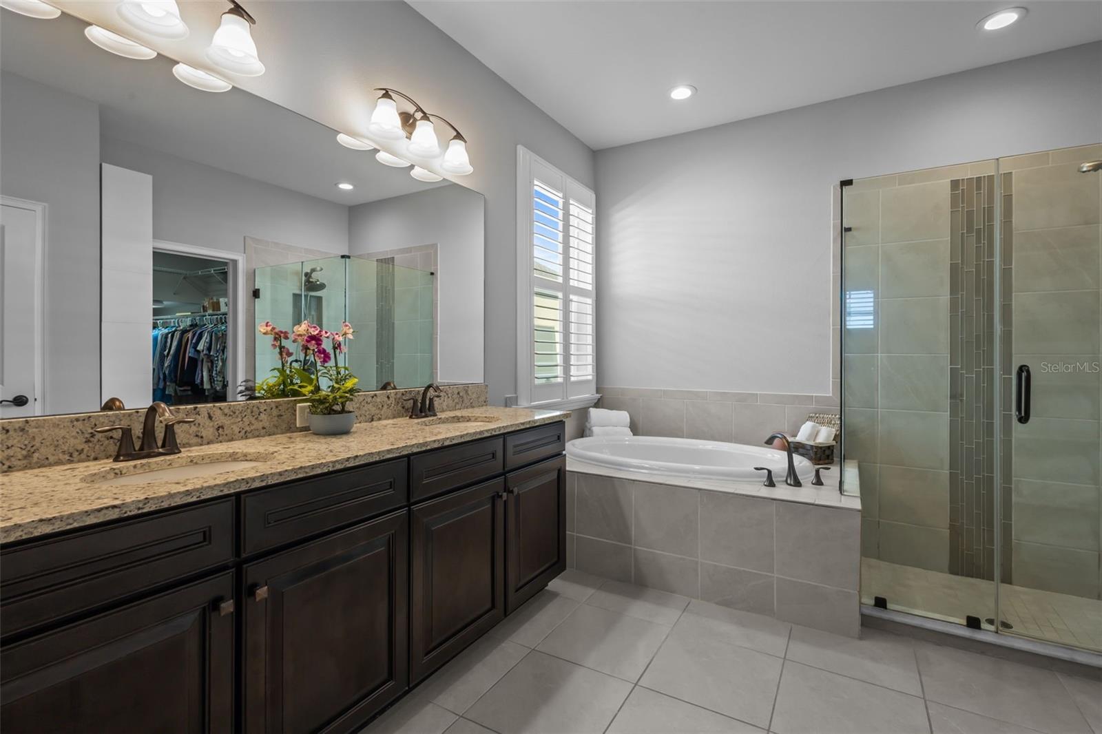 En suite bathroom with double sinks, frameless shower, and garden tub
