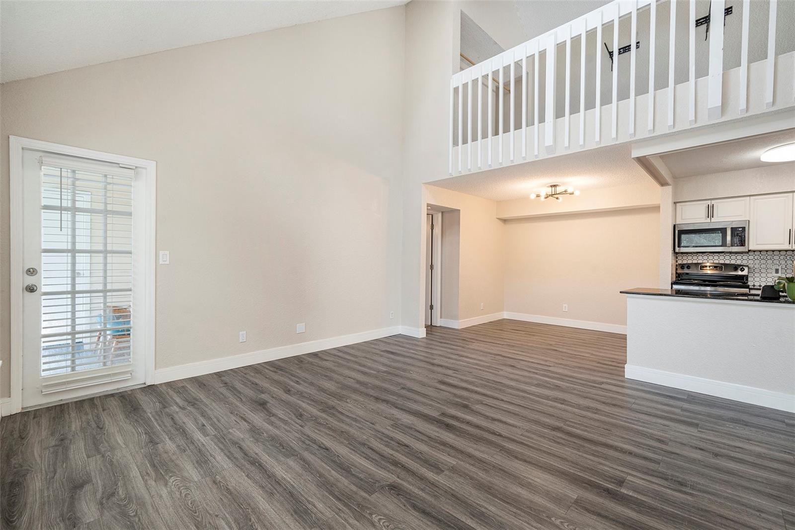 Living room, access to balcony, view to loft, dining space in rear of photo
