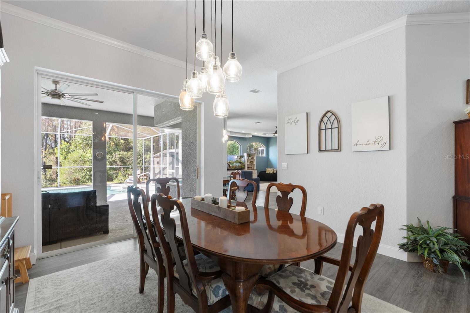 Crown molding adorns the walls of this living area. Sliding glass doors lead out to the pool.