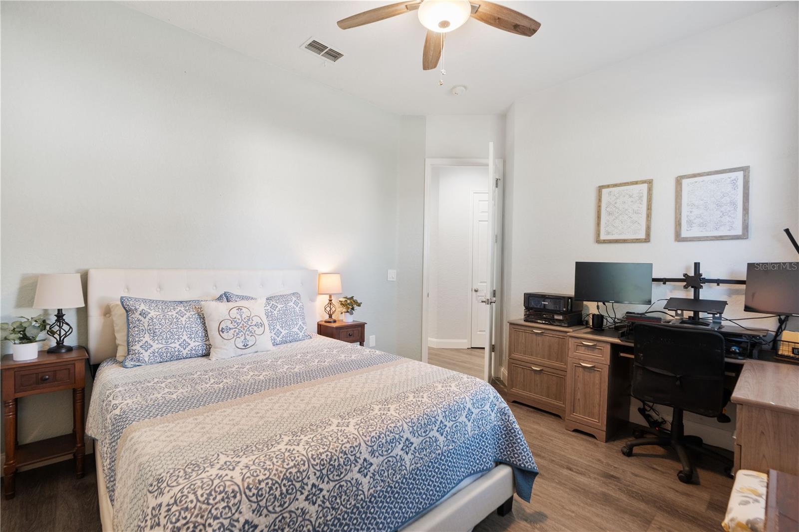 Ceiling fan with light kit, and luxury vinyl flooring, just outside the bedroom is bathroom that separates the two bedrooms and a linen closet in the hall.