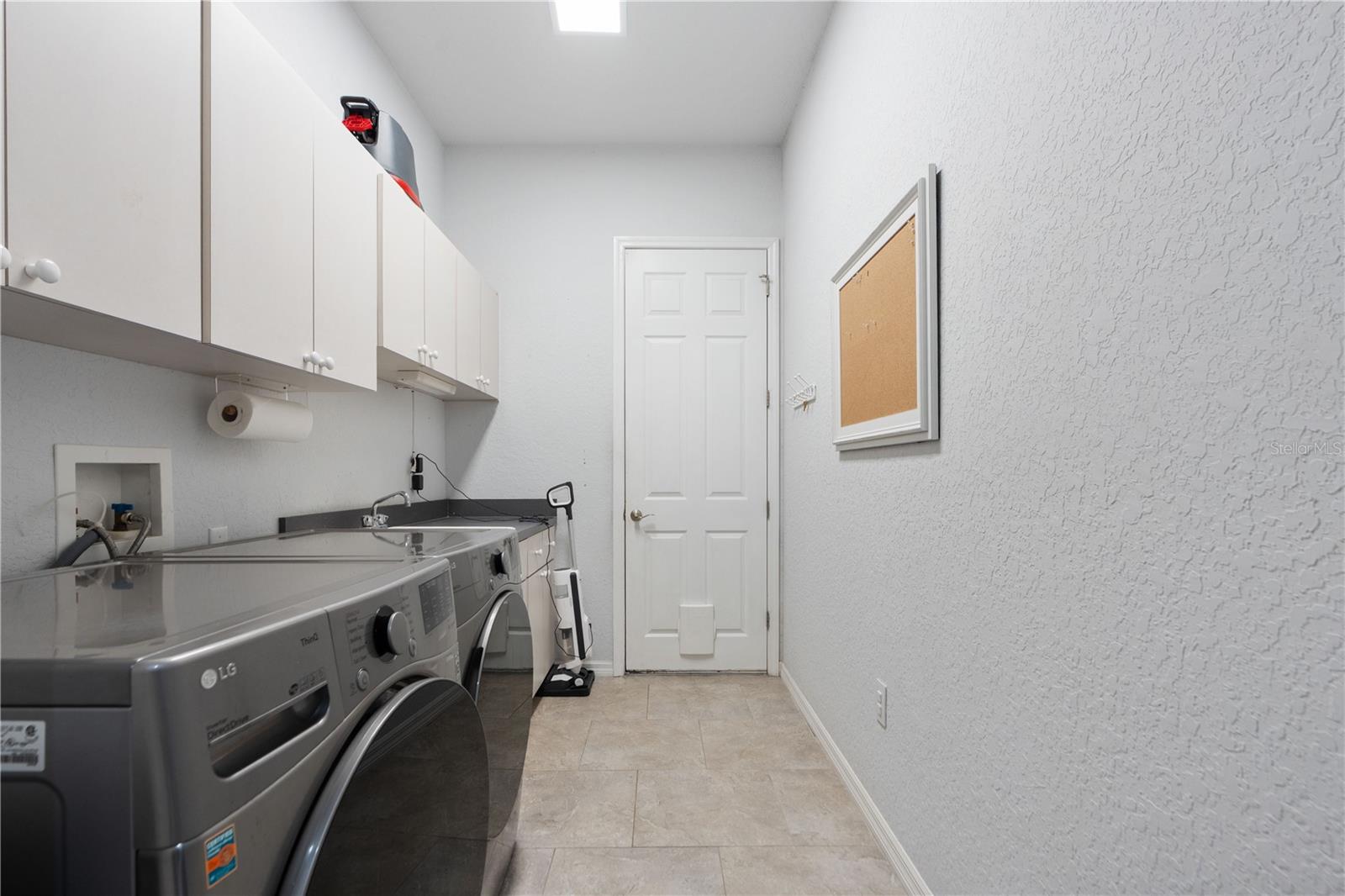 Indoor utility has a cat door that leads to the garage, extra sink and cabinets.