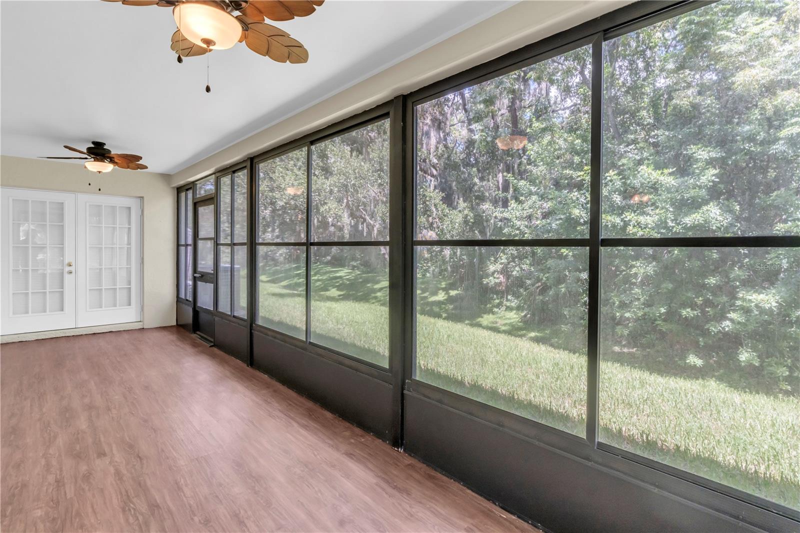 BACK SCREENED LANAI; DOUBLE FRENCH DOORS IN THE DISTANCE LEAD BACK INTO THE LIVING AREA; STEPPING OUTSIDE THE SCREENED DOOR, YOU CAN SEE LOTS OF GREEN AS YOU LOOK LEFT AND RIGHT (AND DOWN; BUT NOT UP...THAT'S USUALLY BLUE)  (1377 MCMULLEN BOOTH RD)