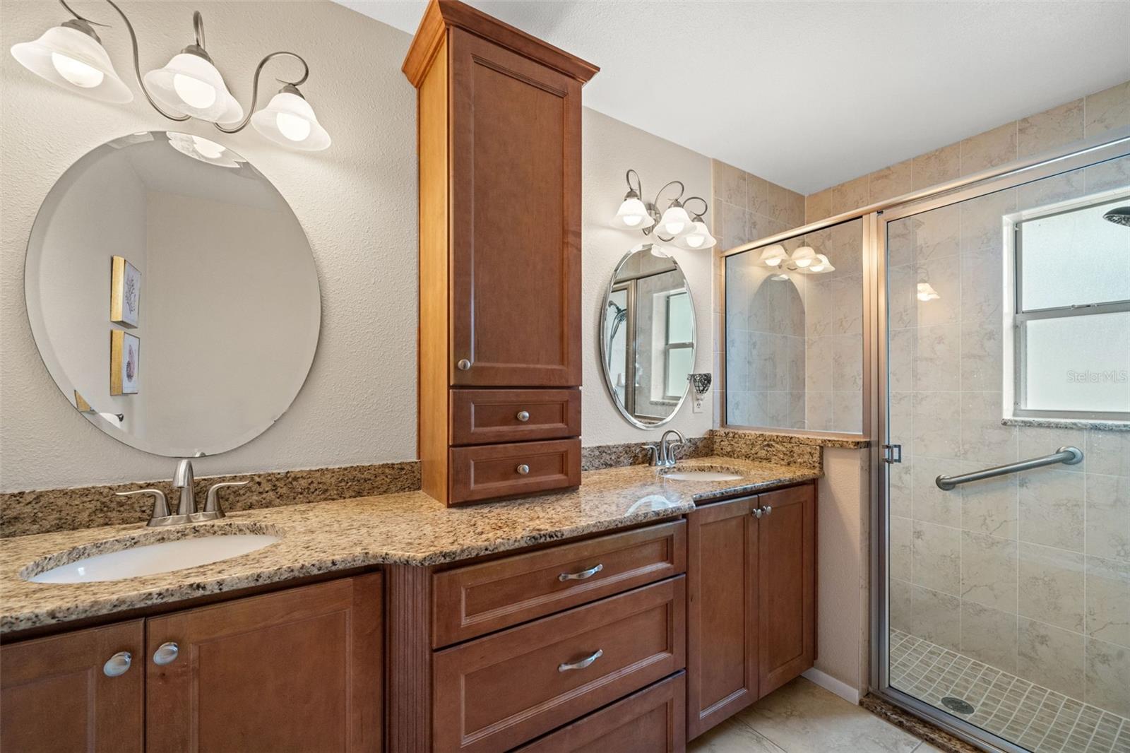 Master Bath with generous granite countertop space, custom shelving and a large walk-in shower.