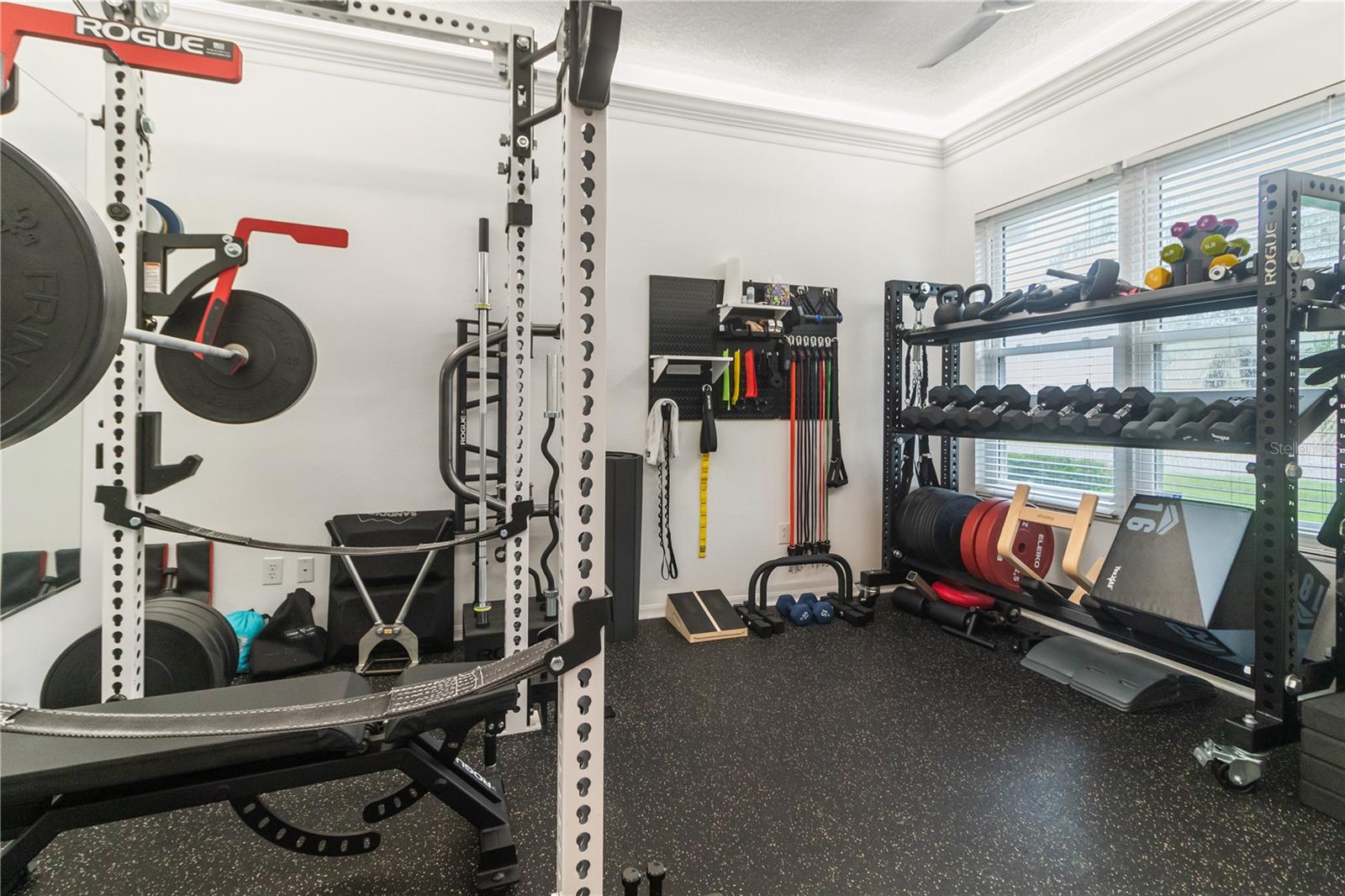 In-home gym with color changin recessed cove lighting, almost full wall mirror and professionally installed rubber flooring