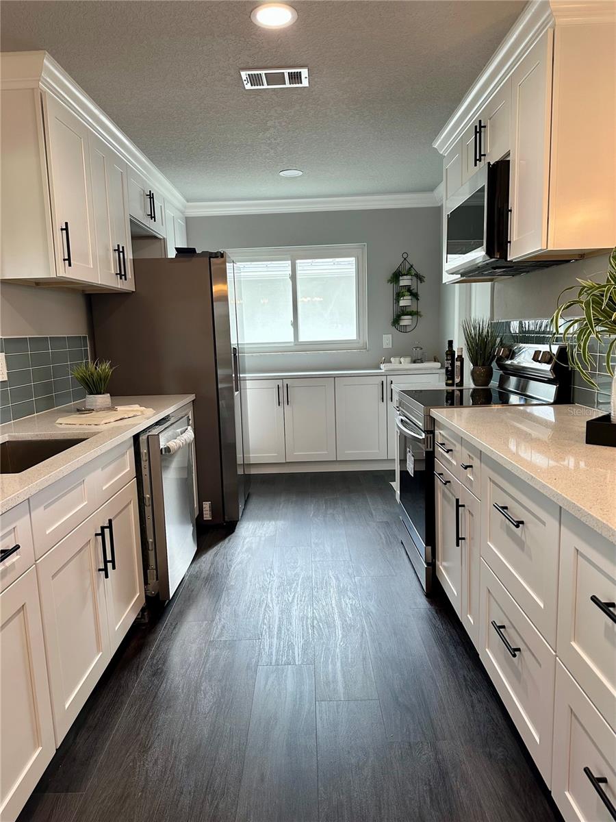 Kitchen with new solid wood cabinets, quartz countertops, all new stainless steel appliances, beautiful tile backsplash, recessed lighting, and more.