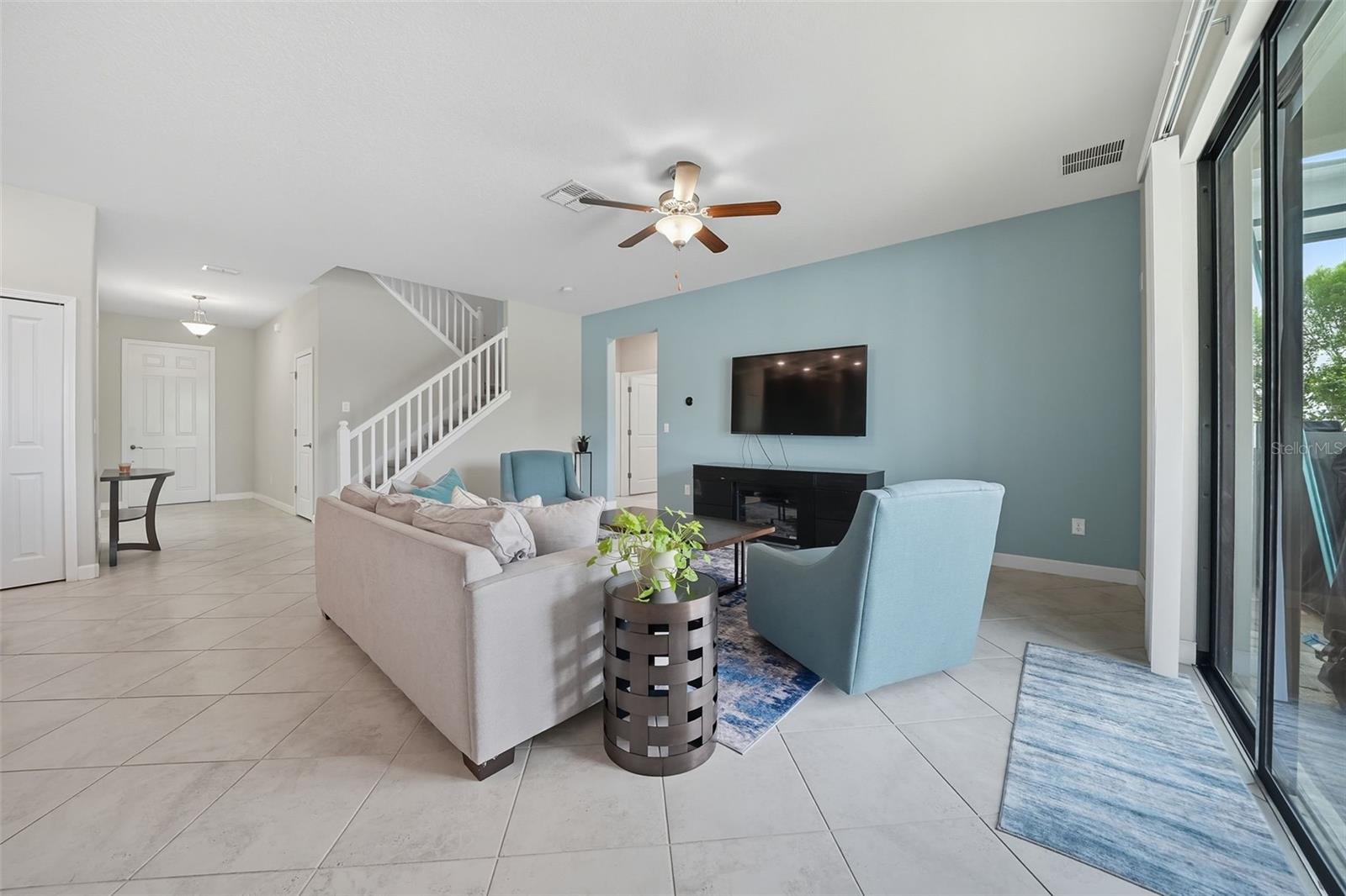 Light-filled living room with durable tile flooring and direct access to the screened patio and pool. Open staircase adds style while connecting seamlessly to the home’s spacious layout