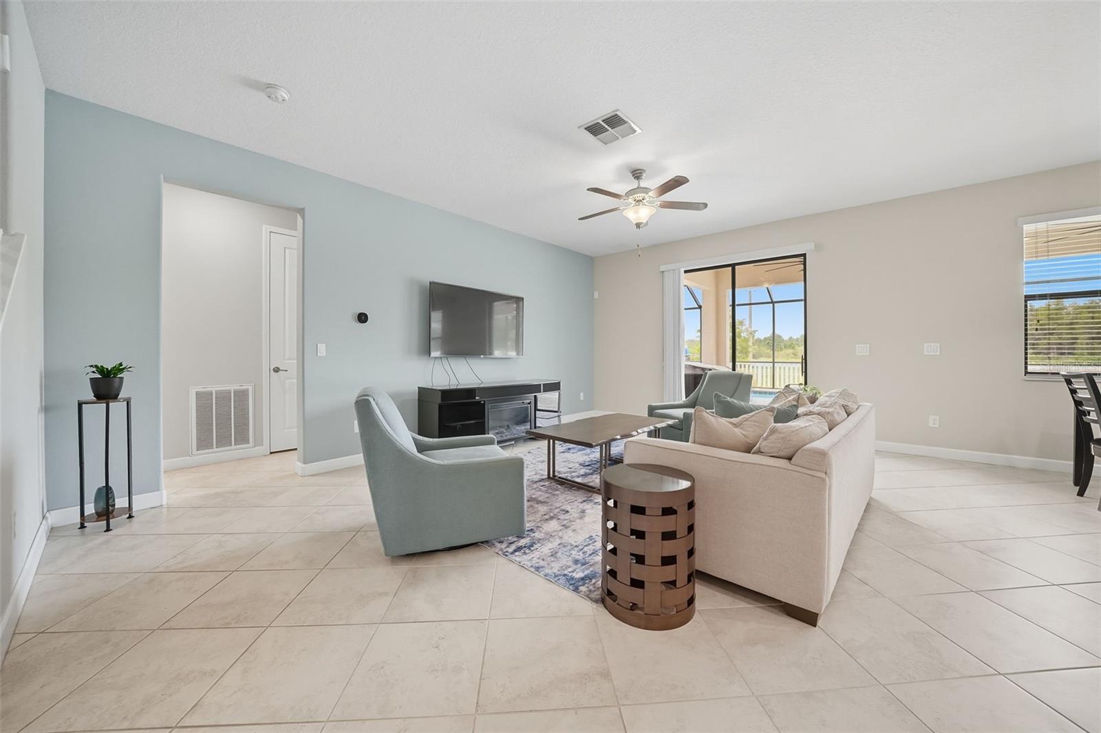 Enjoy relaxing in the spacious living room with tile flooring and direct views of the screened pool and backyard through large sliding doors. Indoor–outdoor living at its best!