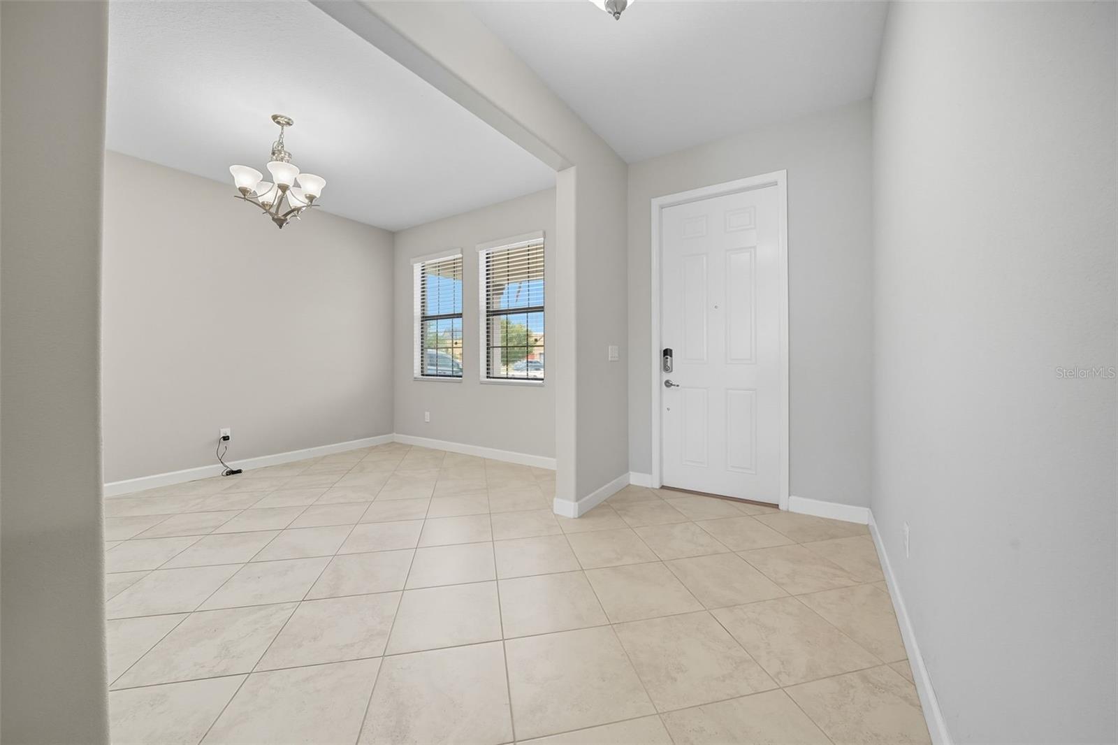 Formal dining room located just off the entrance, featuring tall ceilings, elegant tile flooring, and abundant natural light—creating a grand first impression as you step inside