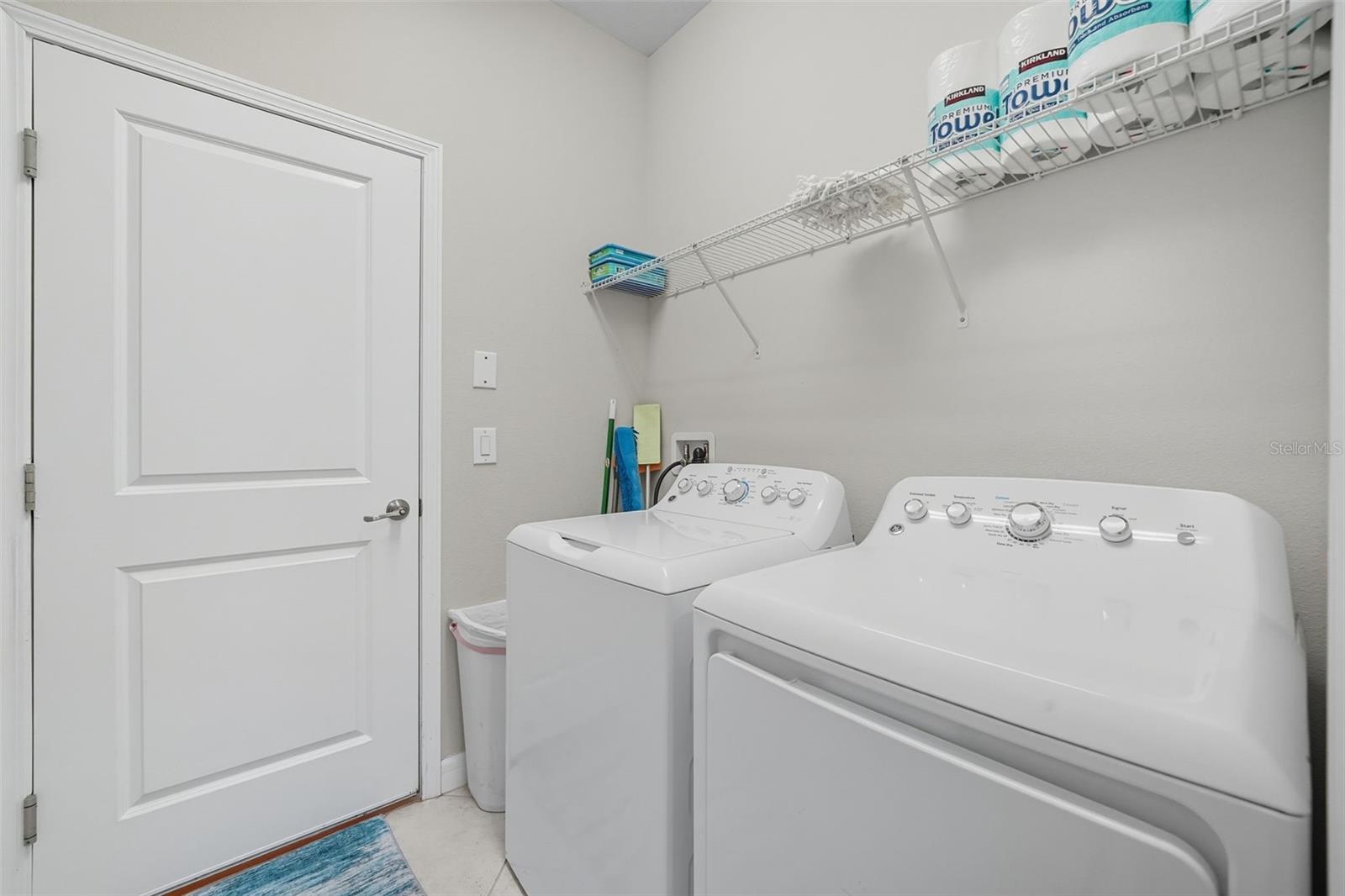 Convenient laundry room with washer and dryer included, plus shelving for extra storage and organization