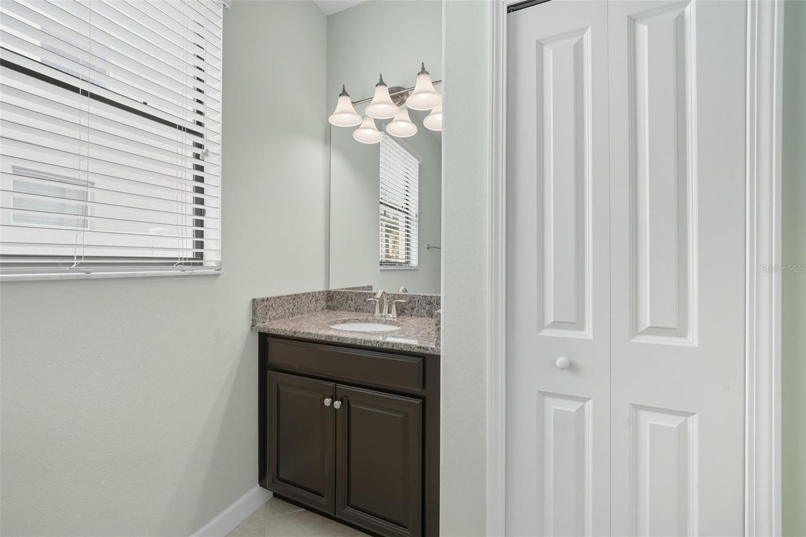 Downstairs bathroom with granite vanity, stylish lighting, and storage—conveniently located for guests and poolside access.