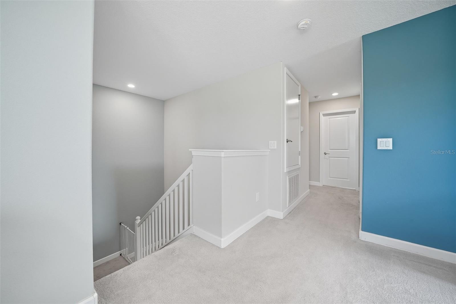 Bright upstairs hallway with easy access to bedrooms, loft, and laundry. Open stairway design adds flow and natural light