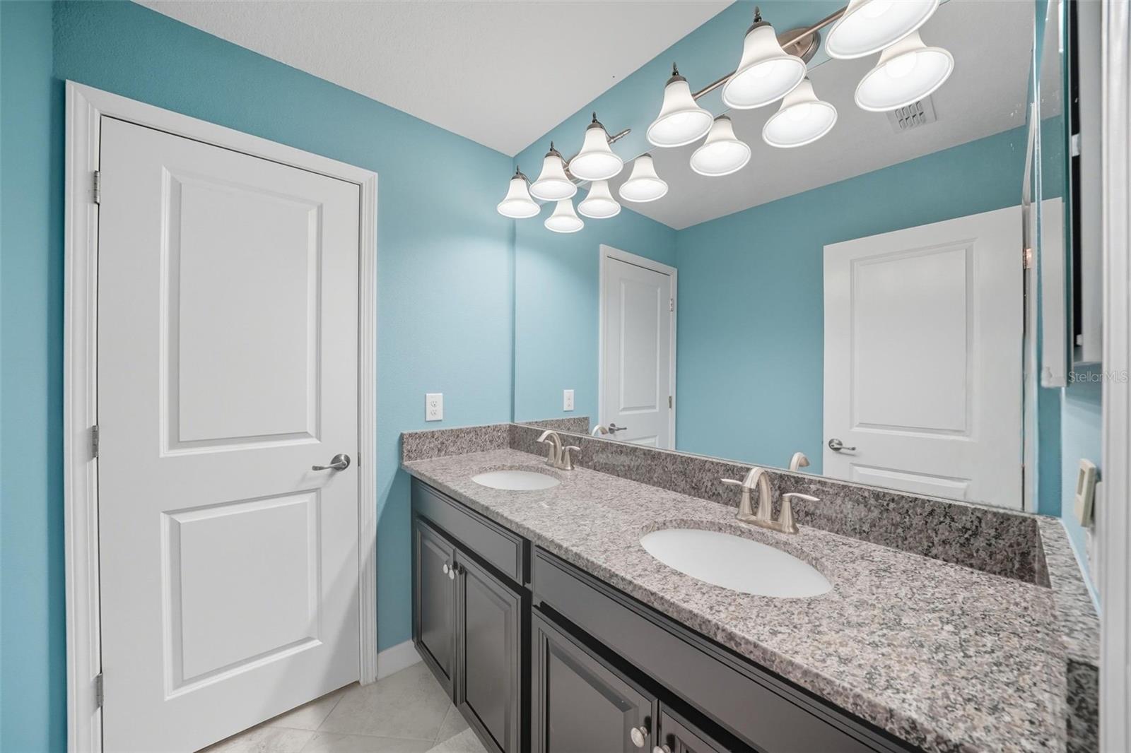 Spacious upstairs bathroom with granite double vanity, modern lighting, and plenty of storage—perfect for busy mornings