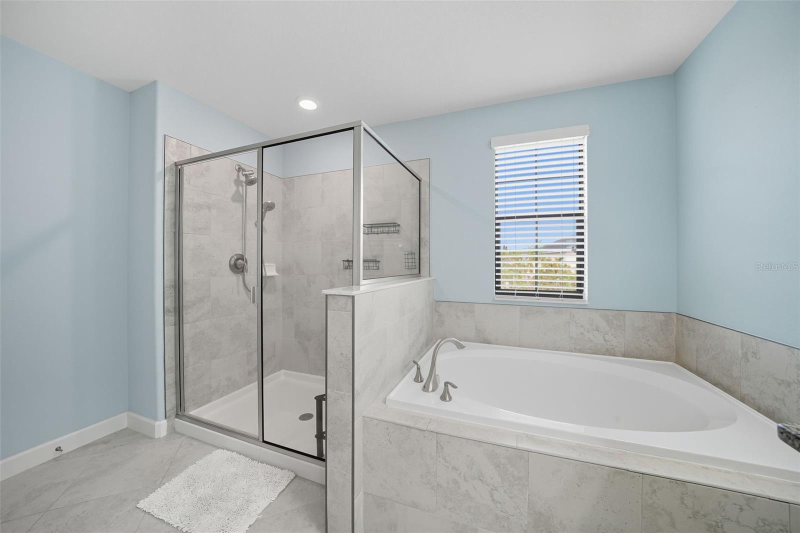Luxurious ensuite featuring a soaking tub, separate glass-enclosed shower, and elegant tile finishes—designed for both relaxation and function