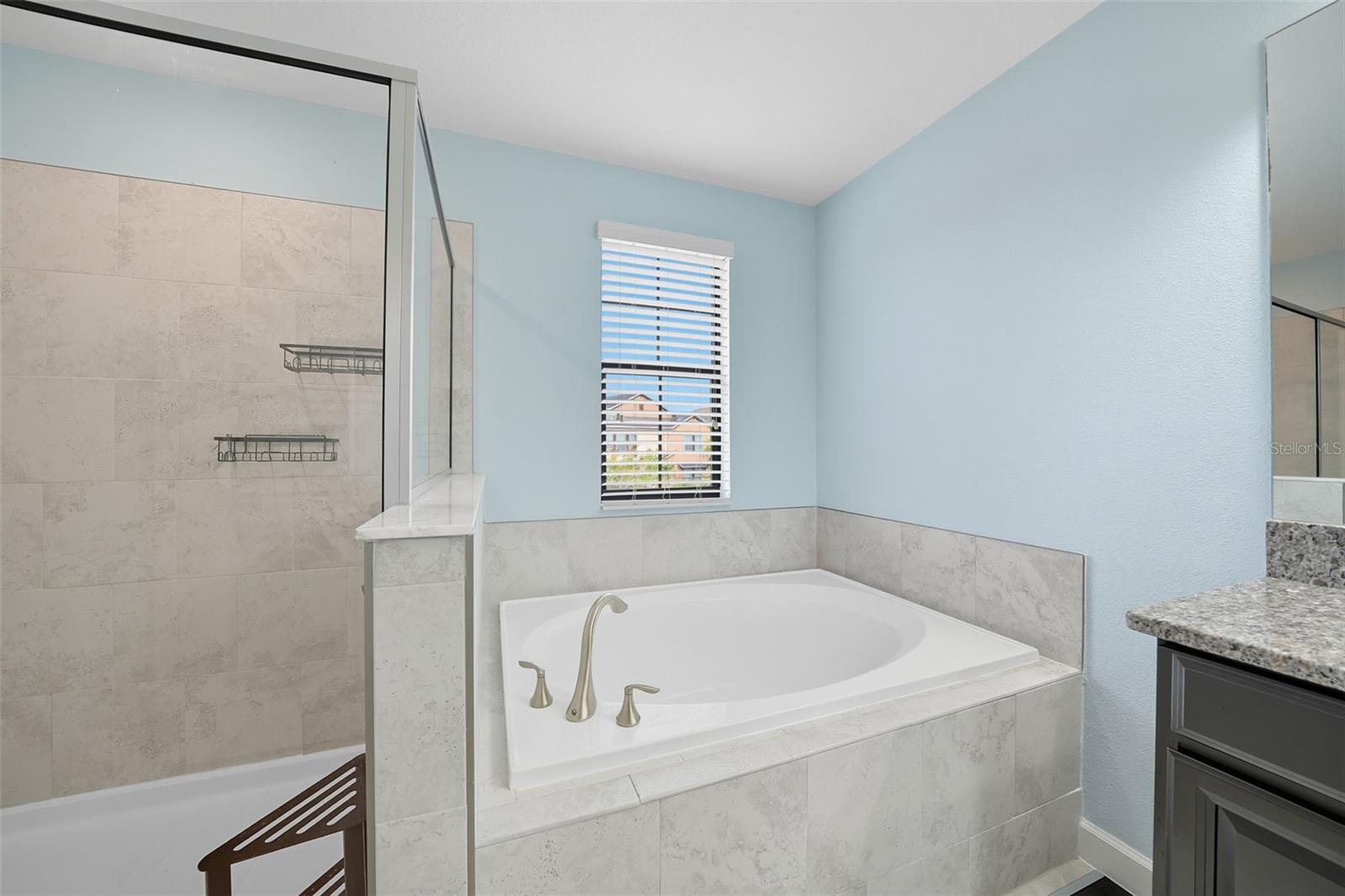 Enjoy the luxury of a soaking tub framed in modern tile, perfectly complemented by the adjacent walk-in shower
