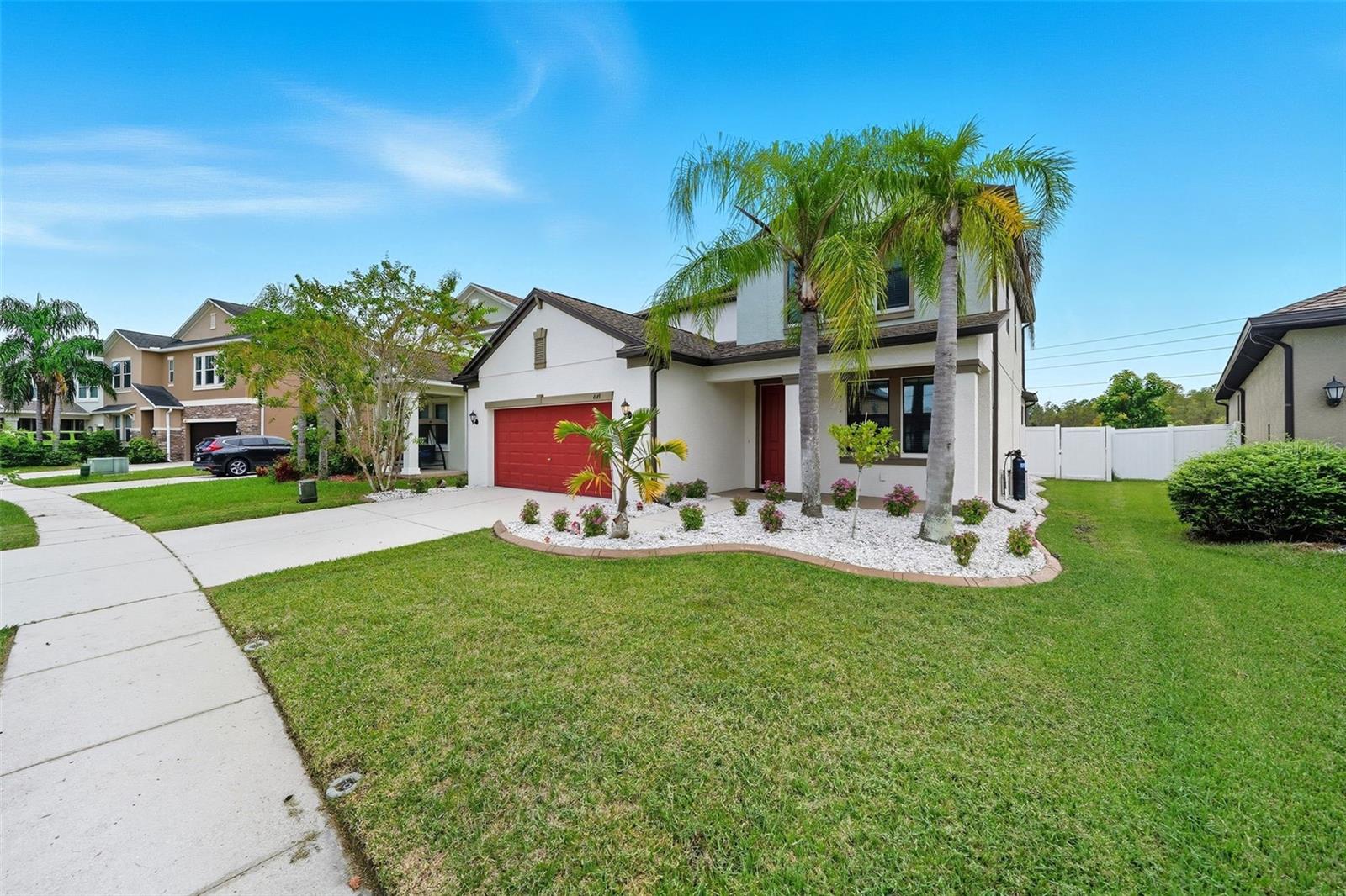 Lush green lawn, tropical palms, and fresh landscaping frame the front of this home beautifully. The welcoming front porch and modern exterior details make a lasting first impression