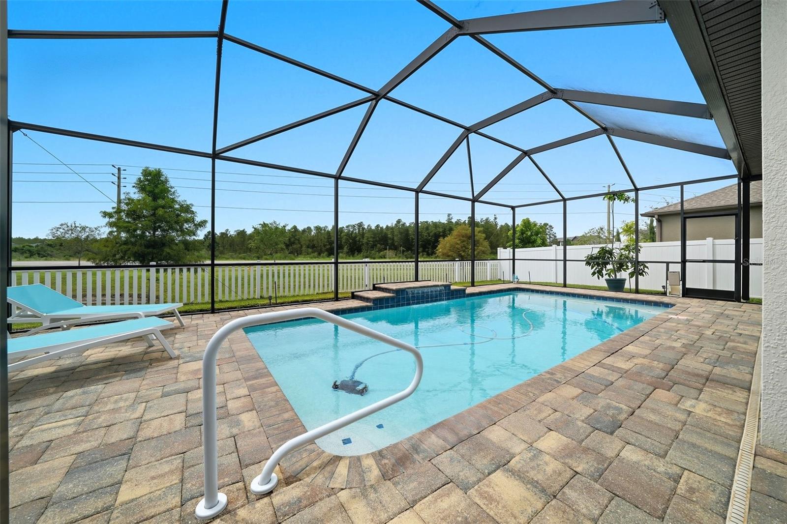 Enjoy Florida living with a sparkling screened-in pool featuring a paver deck, step entry, and soothing water feature — all overlooking a peaceful conservation view