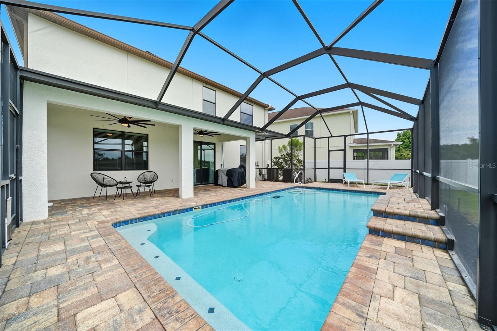 Enjoy the best of Florida living with a covered lanai featuring dual ceiling fans, paver decking, and a sparkling screened-in pool — perfect for relaxing or entertaining year-round