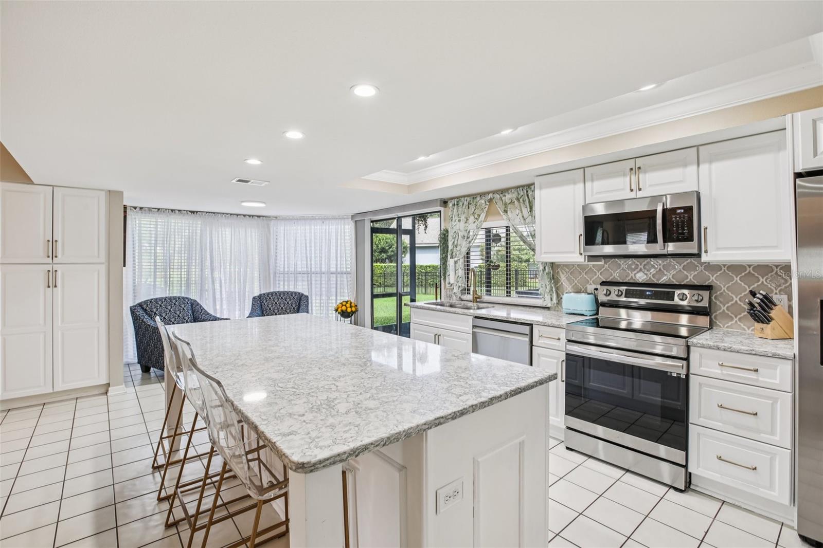 Beautifully renovated open kitchen with quarts countertops, center island,  soft close cabinets, new appliances, overhead lighting and beautiful back splash