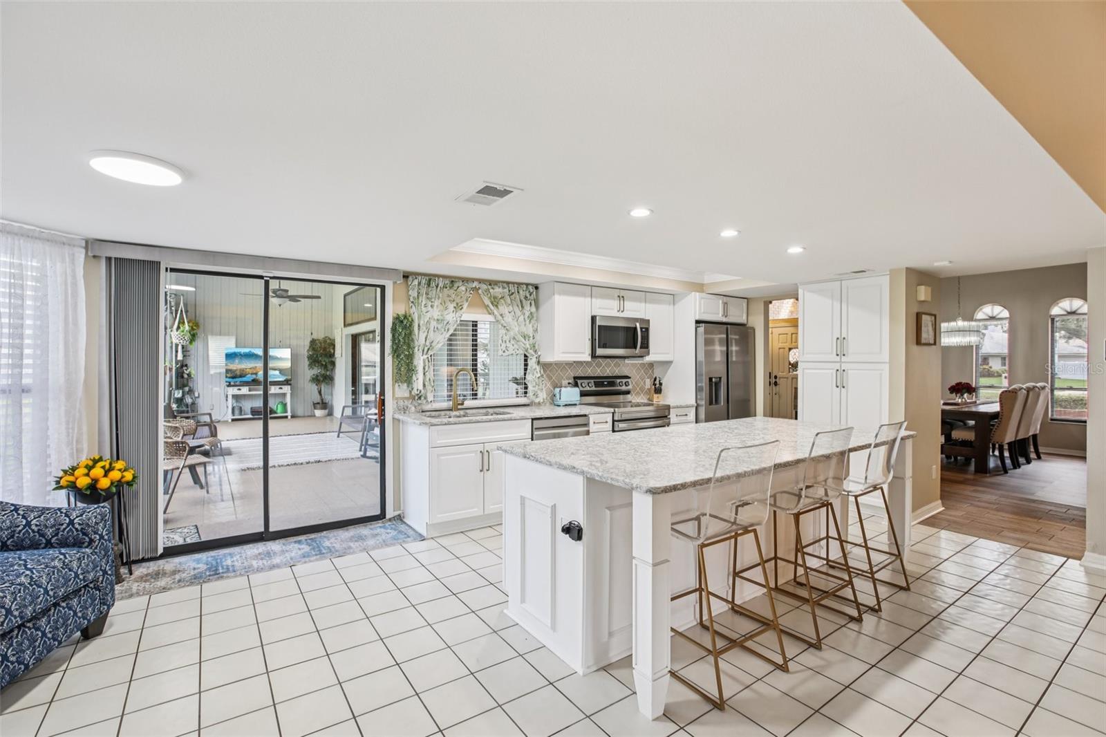 Beautifully renovated open kitchen with quarts countertops, center island,  soft close cabinets, new appliances, overhead lighting and beautiful back splash.  Sliders open to lanai