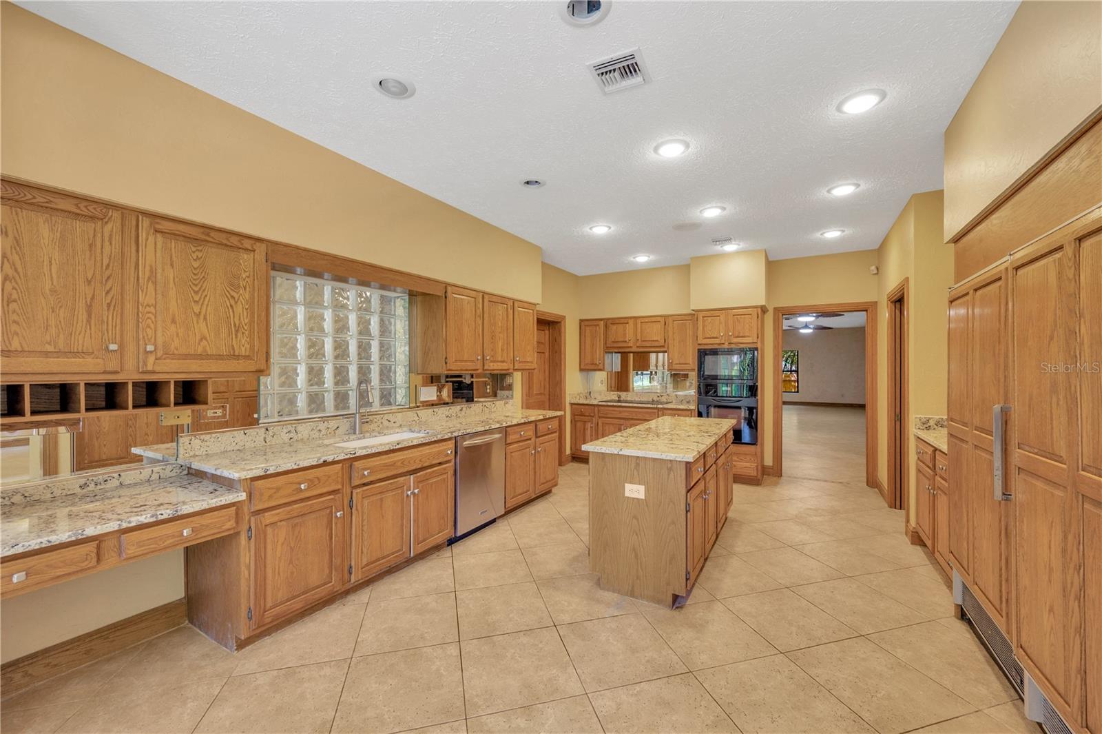 Chef’s dream kitchen—equipped with a Sub-Zero refrigerator and freezer, induction cooktop with anti-scratch matte glass, granite countertops, a center island, walk-in pantry, and a spacious eat-in area