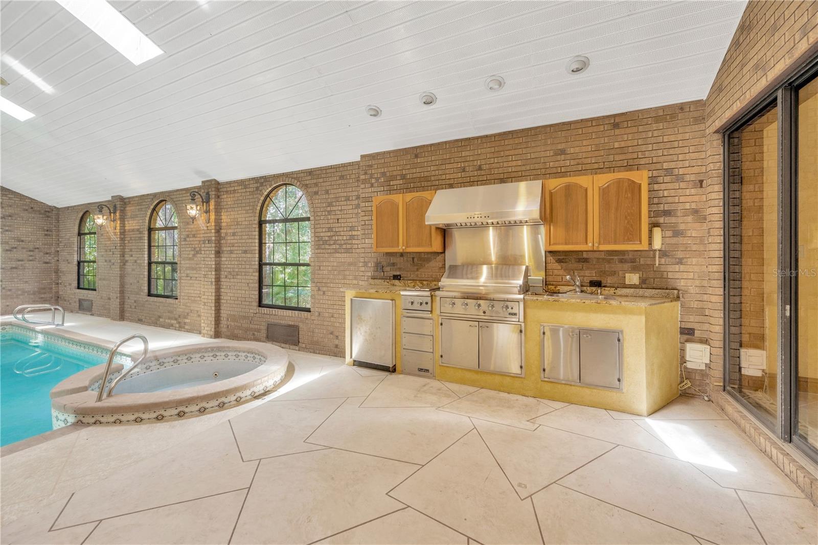 The indoor Atrium includes a DCS outdoor kitchen, complete with gas grill, Thermador hood, refrigerator, and sink