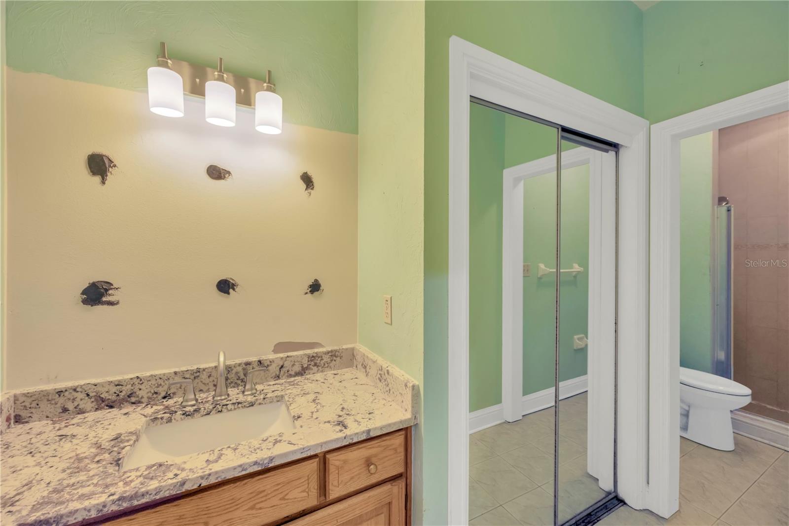 Pool side full bathroom with granite vanity (Mirror to be replaced), storage, toilet, urinal & shower.