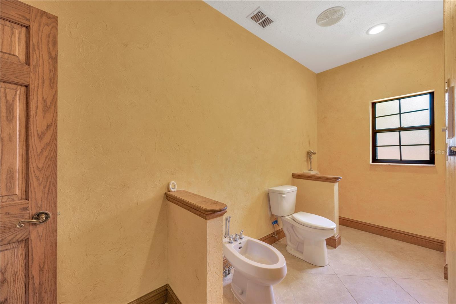 Bidet & Toilet with small privacy wall.  Urinal is located next to the window wall.