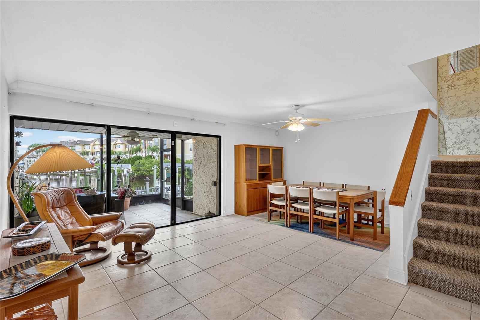Lovely living and dining room with sliders overlooking a balcony and water.