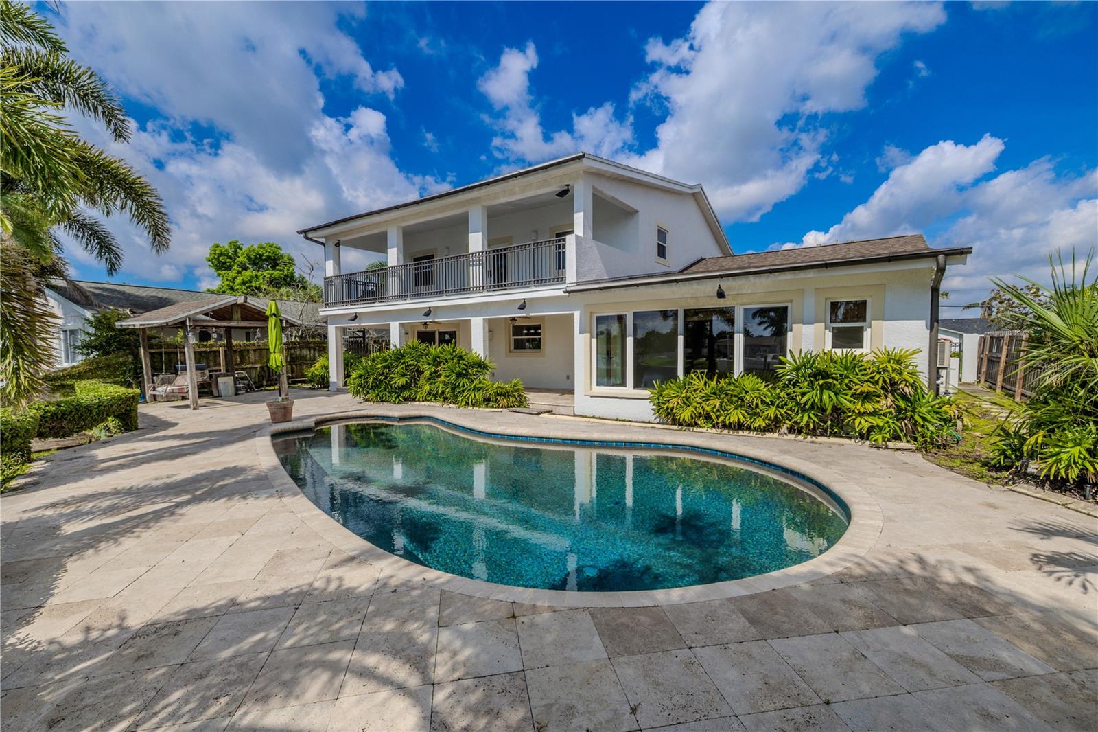 A sparkling, free-form pool is the centerpiece of the backyard. The pool is framed by elegant travertine coping and an expansive travertine deck, creating a timeless and upscale look that stays cool underfoot. Surrounded by lush tropical landscaping, the outdoor space offers both beauty and privacy.