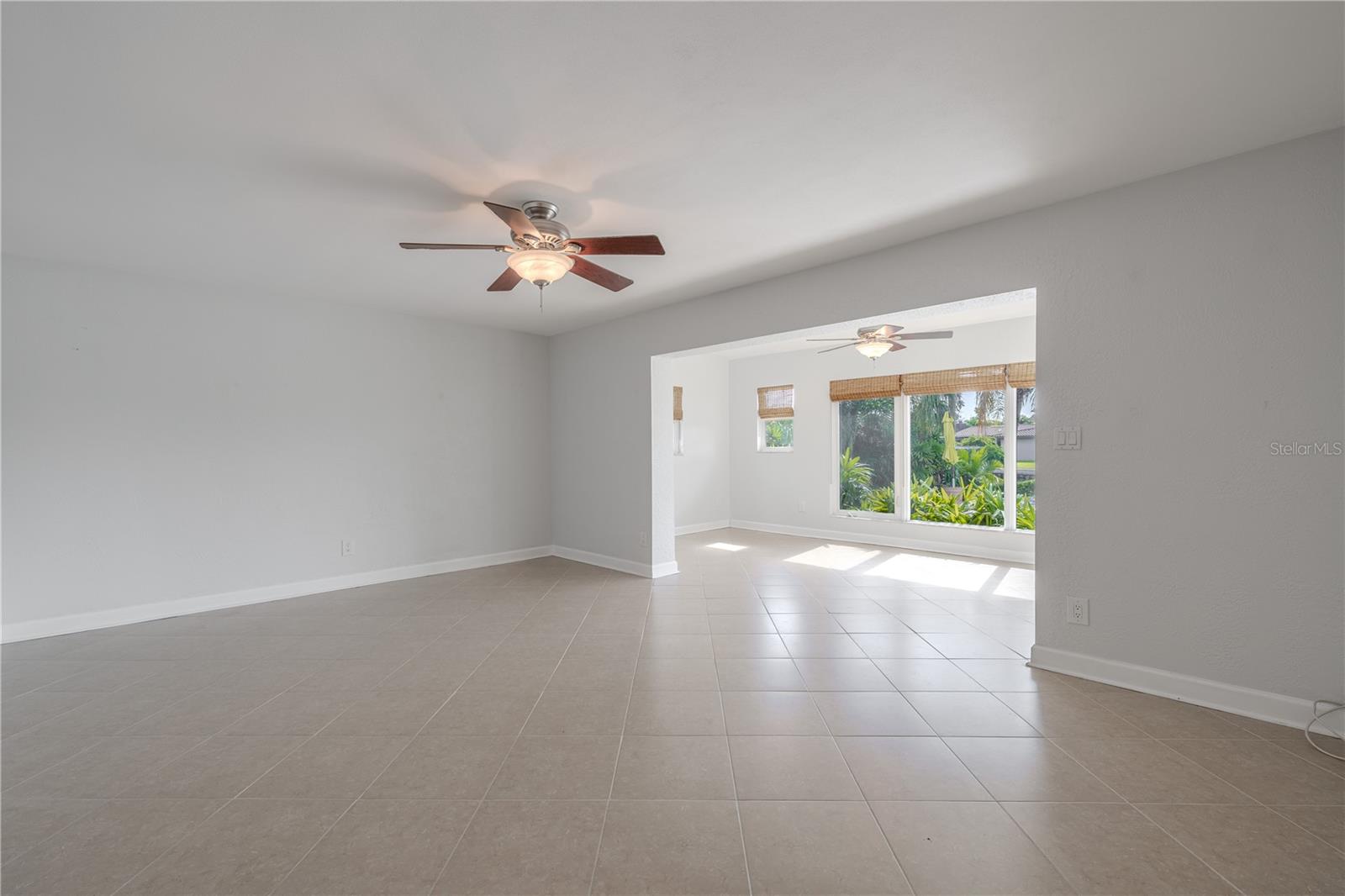 The spacious family room offers a comfortable gathering space with neutral tile flooring, soft wall tones, and a ceiling fan for year-round comfort. Its open layout makes it a versatile hub.