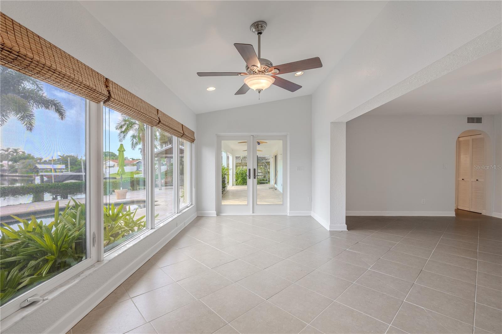 The Florida room offers a bright, relaxing space with triple-paned, hurricane-rated windows and glass doors that frame stunning views of the pool and canal while adding peace of mind. Neutral tile flooring and a ceiling fan create comfort and style, while French doors open directly to the covered patio for effortless indoor-outdoor living. With its natural light and water views, this versatile room is perfect as a sunroom, casual sitting area, or home office.