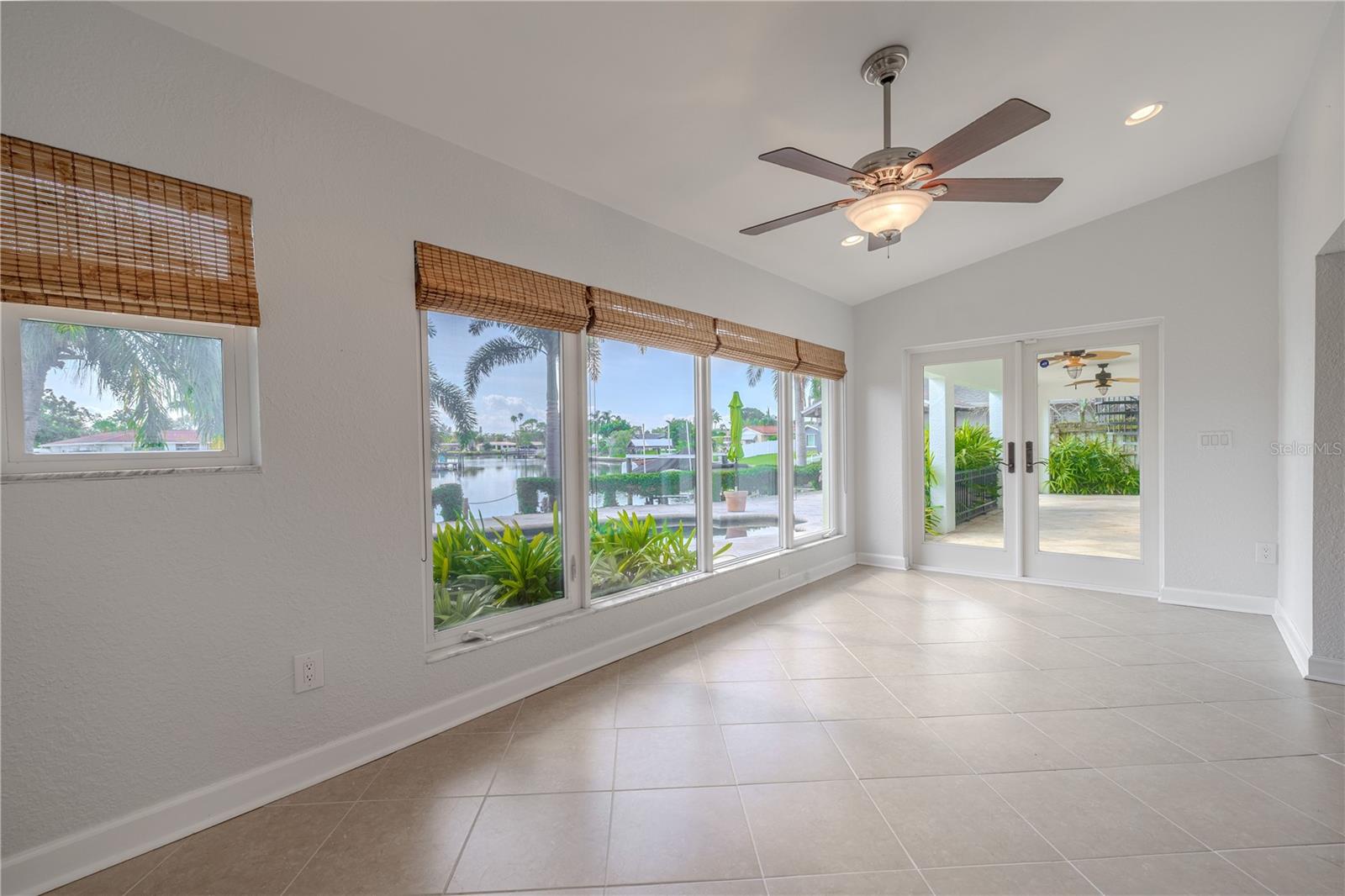 The light-filled Florida/Sun Room with expansive picture windows overlooking the pool and canal, brings the outdoors in. Neutral tile flooring and a ceiling fan ensure year-round comfort, while double French doors open directly to the covered patio and backyard