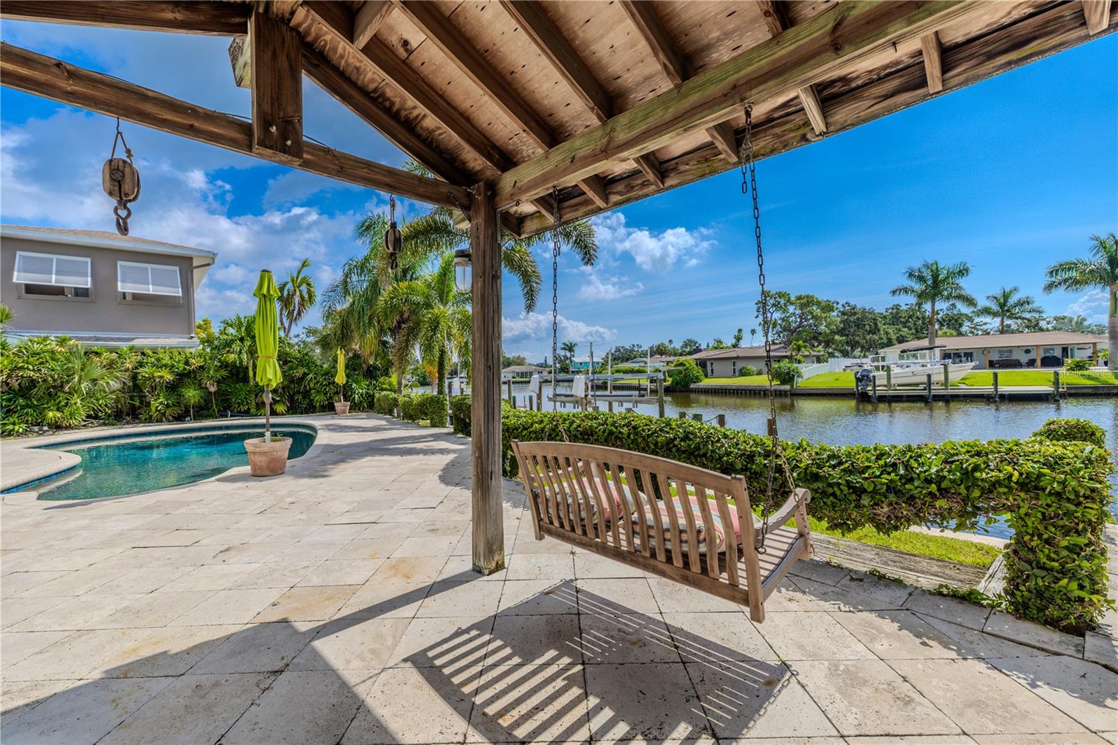The back patio highlights the perfect blend of relaxation and waterfront living. A wooden swing beneath a pergola-style cover creates a charming spot to enjoy the breeze and canal views.