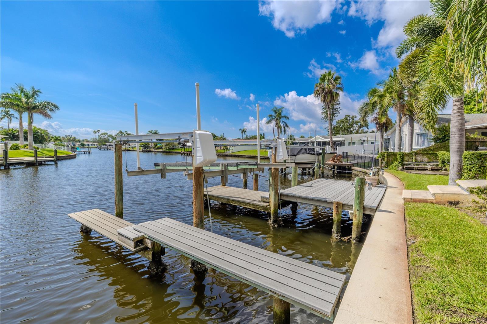 The property features a private dock with durable TREX decking and a 10,000 lb boat lift, set on a wide canal with direct bay access.
