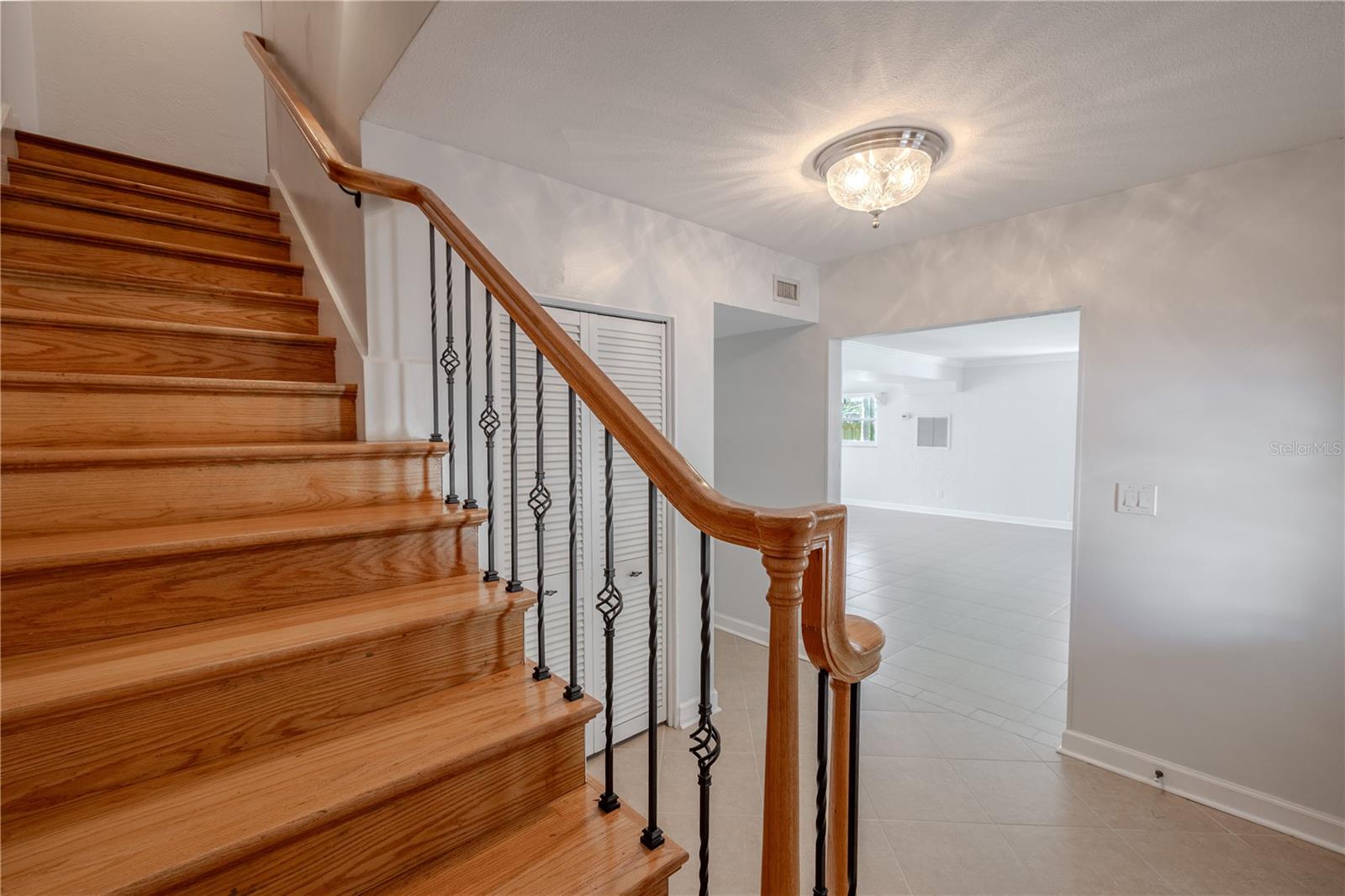 The home welcomes you with a bright entryway featuring gleaming hardwood stairs accented by wrought iron spindles and a polished wood handrail. Overhead, a Waterford crystal light fixture casts an elegant glow, setting a refined tone for the rest of the home.