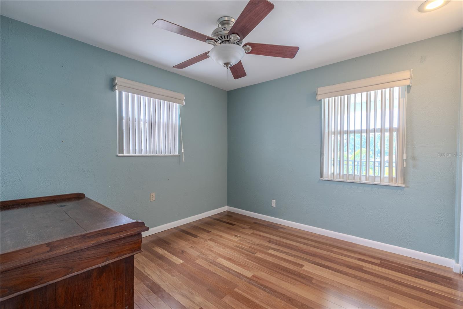 The third bedroom features Brazilian Teak solid wood flooring, carried throughout the second-floor hallways, bedrooms, and closets. Two windows bring in abundant natural light, while a modern ceiling fan with light fixture adds comfort.