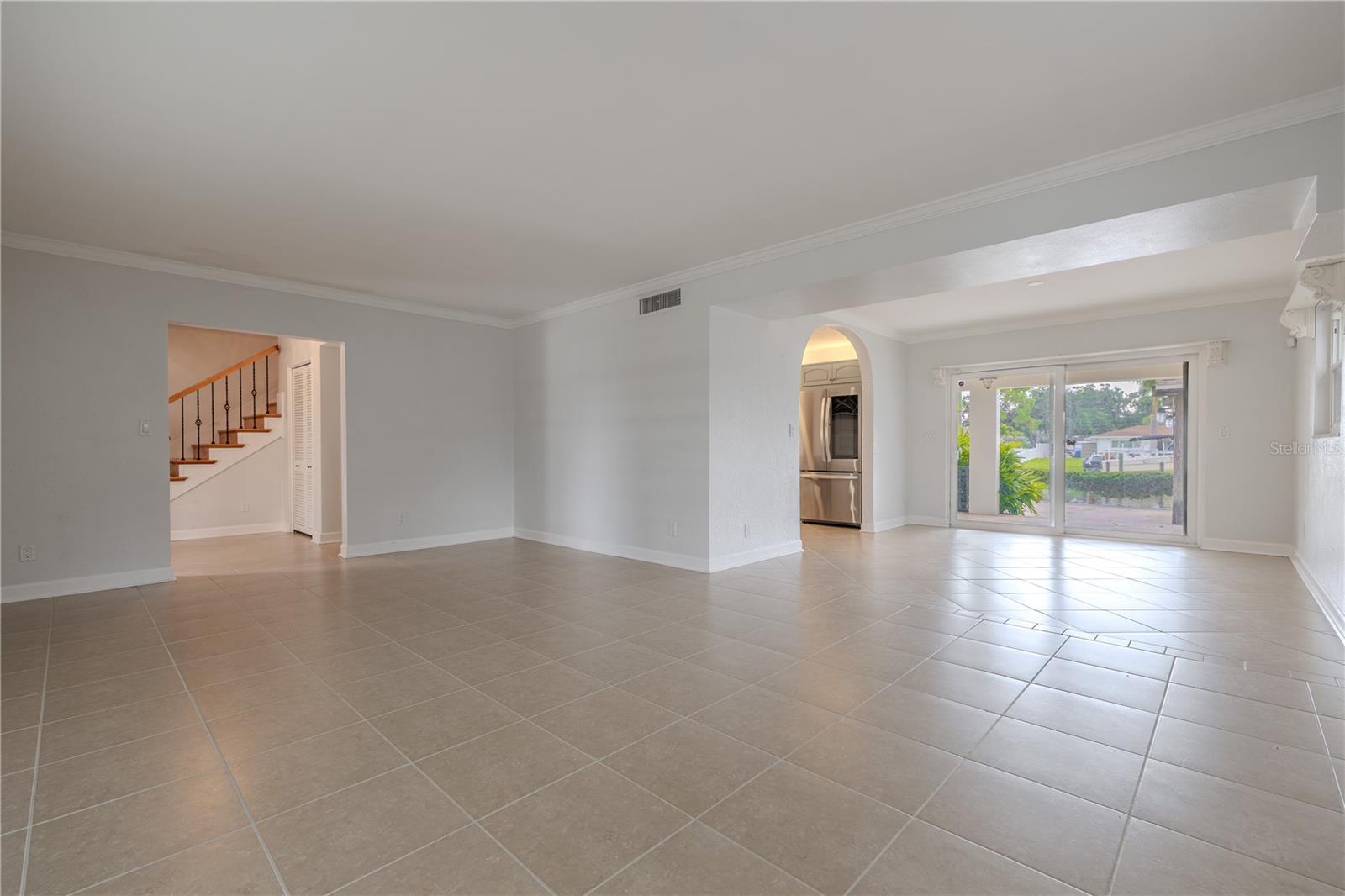 The open-concept living and dining areas create a bright and versatile flow. Neutral tile flooring runs throughout, enhancing the sense of space and tying the rooms together. The living room opens seamlessly into the dining area, where sliding glass doors frame views of the backyard and canal, allowing natural light to pour in and extending the living space outdoors.