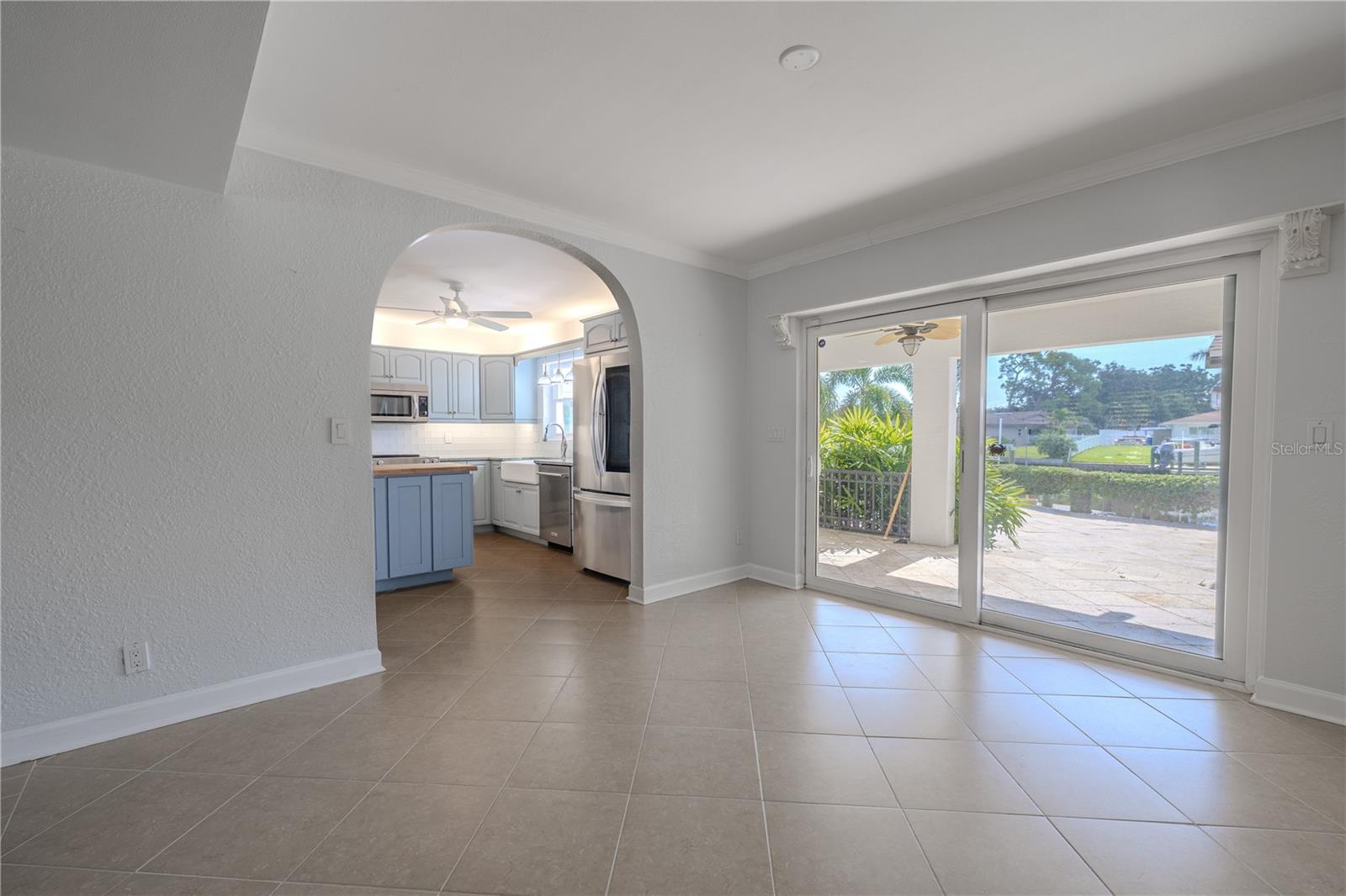 This dining space combines charm and functionality with an arched entry into the kitchen and sliding glass doors that open directly to the covered patio and pool deck.