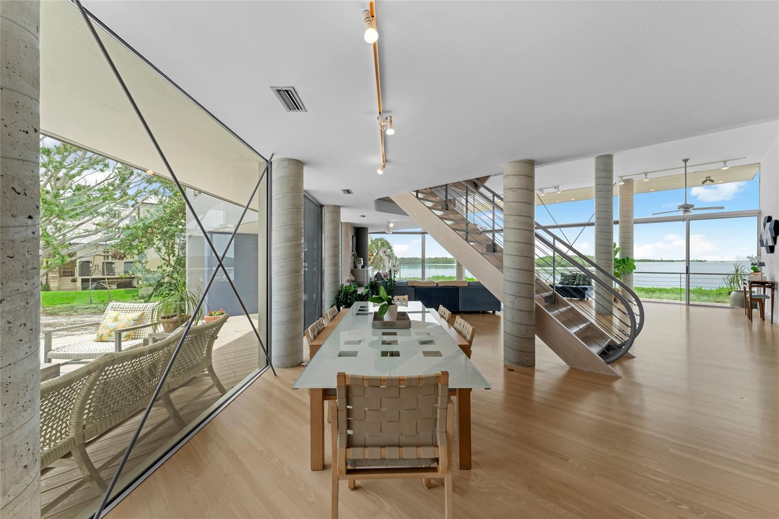An open dining area, framed by architectural columns and uninterrupted views, seamlessly connects the kitchen to the living space.