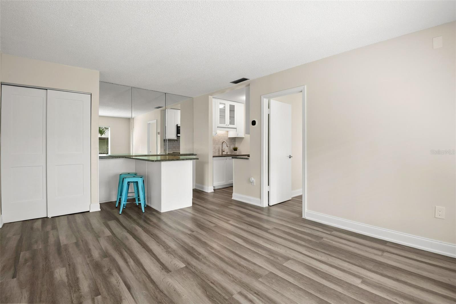 Living area looking at built-in kitchen island, which provides additional cabinet space and wine refrigerator facing the kitchen.