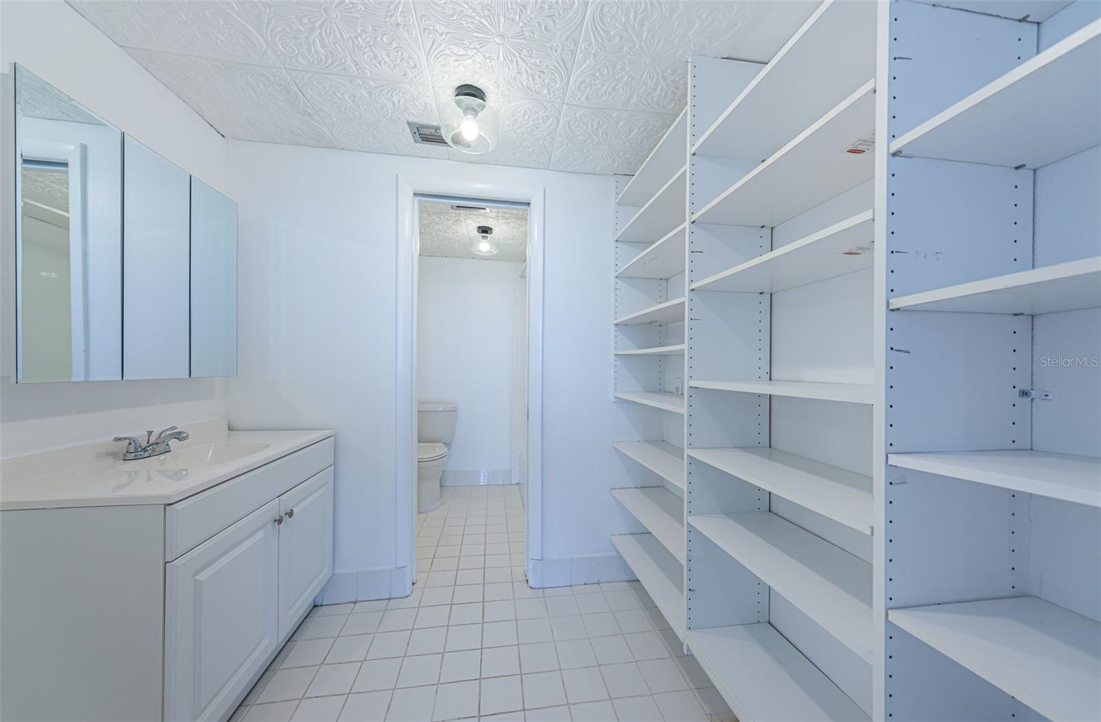 Second bedroom bathroom with walk-in closet and washer hookup behind the shelves