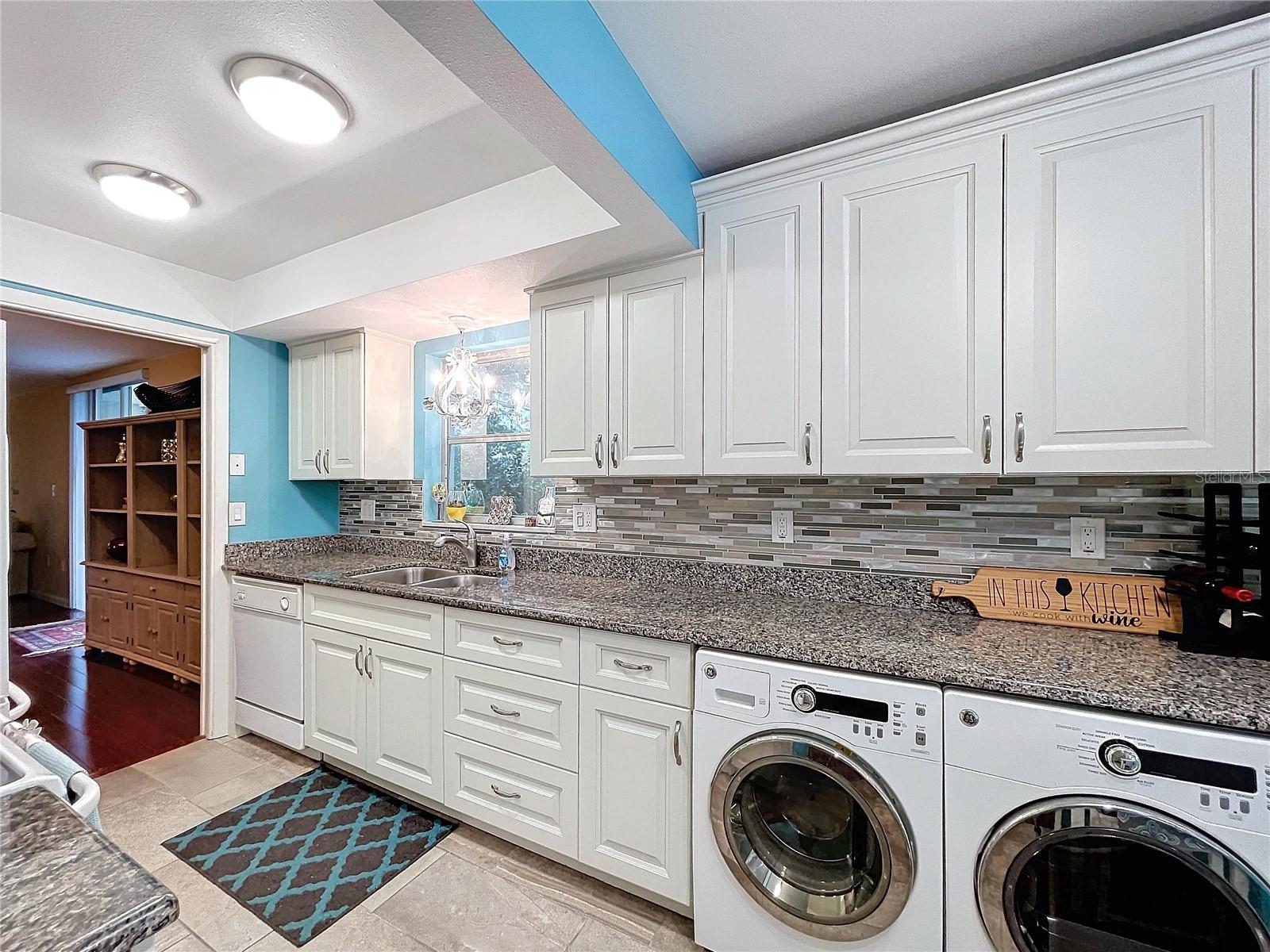 Integrated washer and dryer tucked neatly beneath granite counters, maximizing space and convenience in this efficient design.