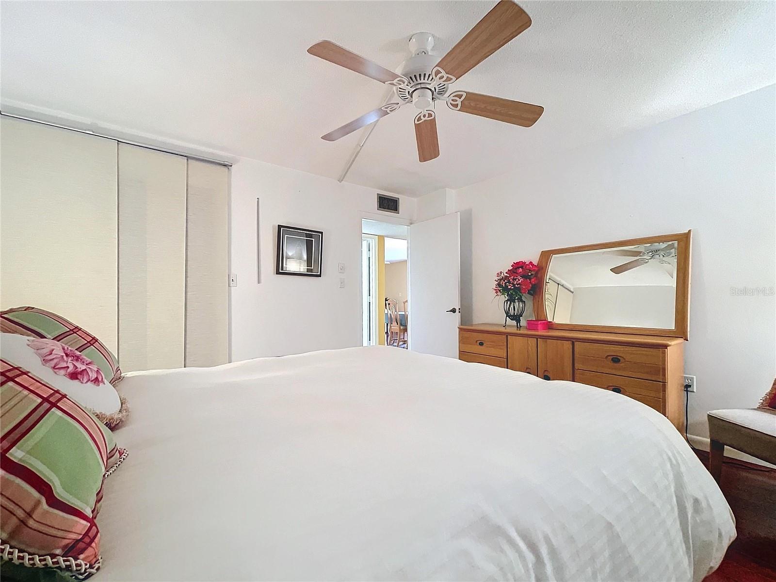 Tranquil bedroom retreat with white walls, rich wood flooring, and a ceiling fan for added comfort. Sliding closet doors provide ample storage.