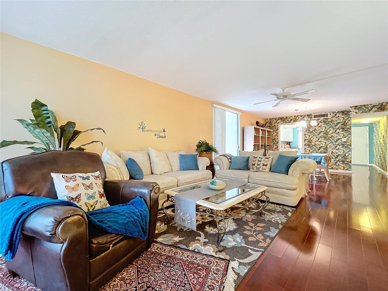 Thoughtfully designed open-concept layout with comfortable seating, ceiling fan, and stylish accent wall leading into the dining area.