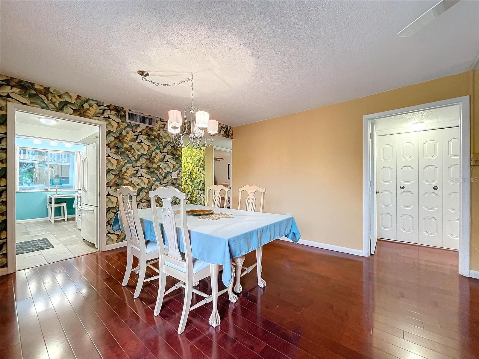The dedicated dining space features a charming chandelier, wood flooring, and access to both the kitchen and entryway for functional flow.