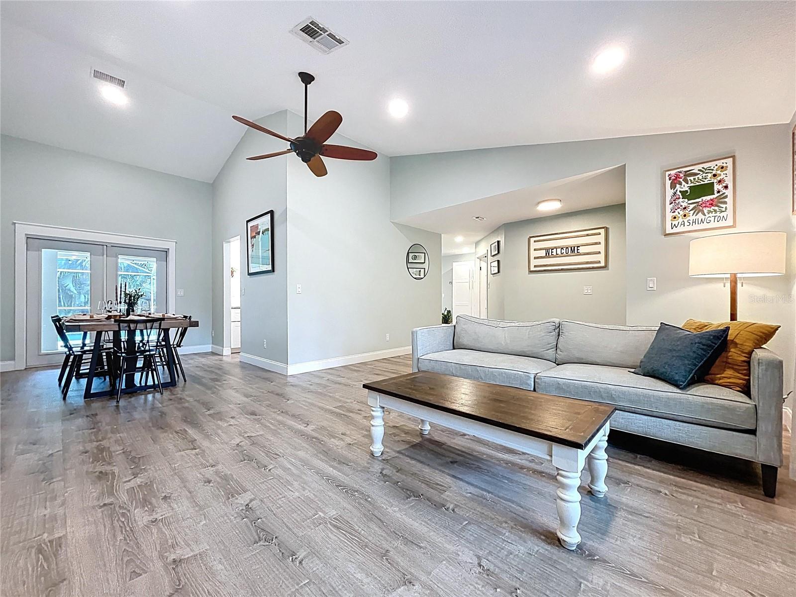 Open-concept layout seamlessly connects the living room and dining space, enhanced by recessed lighting and a modern ceiling fan.