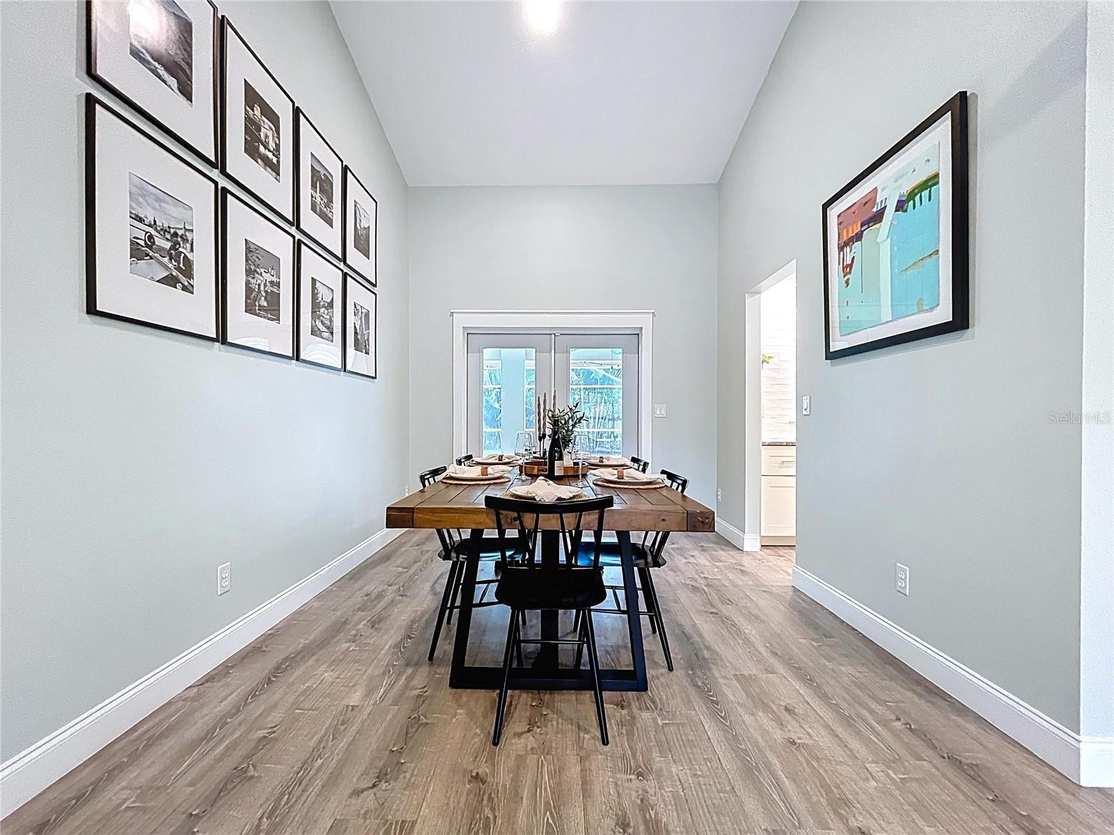 Elegant dining space with gallery-style wall art and direct access to the pool through glass French doors—ideal for indoor-outdoor entertaining.