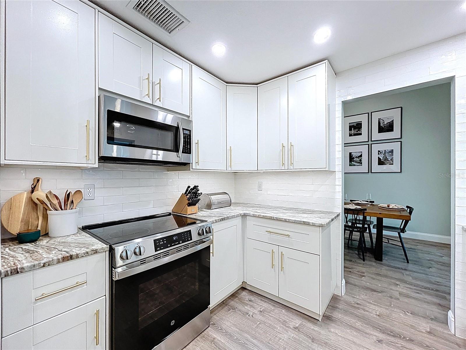 Sleek and functional kitchen showcasing stainless steel appliances, shaker-style cabinetry, and modern gold-tone hardware.