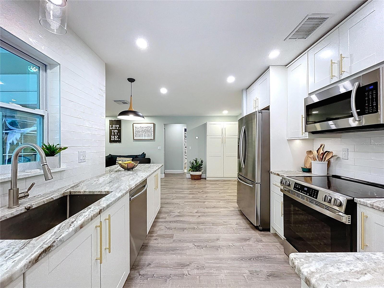 Granite countertops with under-mount sink, large window, and pendant lighting create a light-filled and practical prep zone.