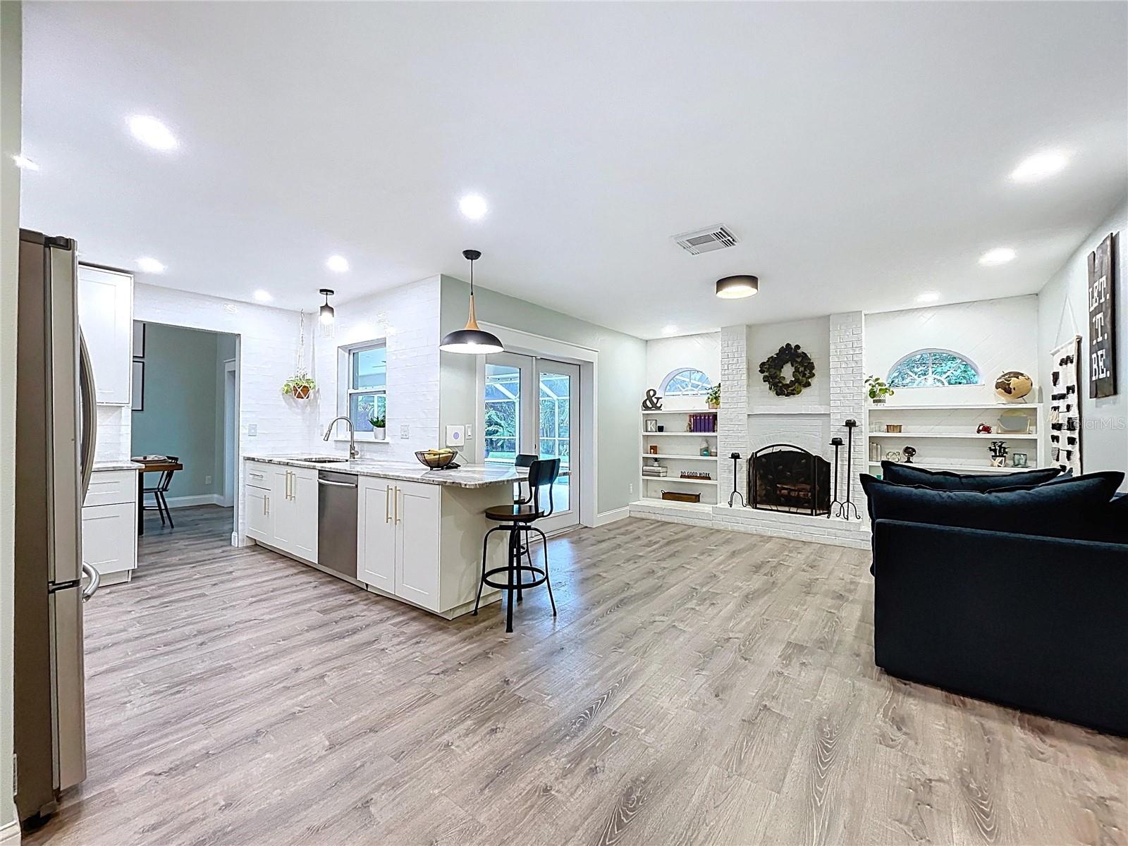 Comfortable family room with built-in shelving, a painted brick fireplace, and dual arched windows for added charm.